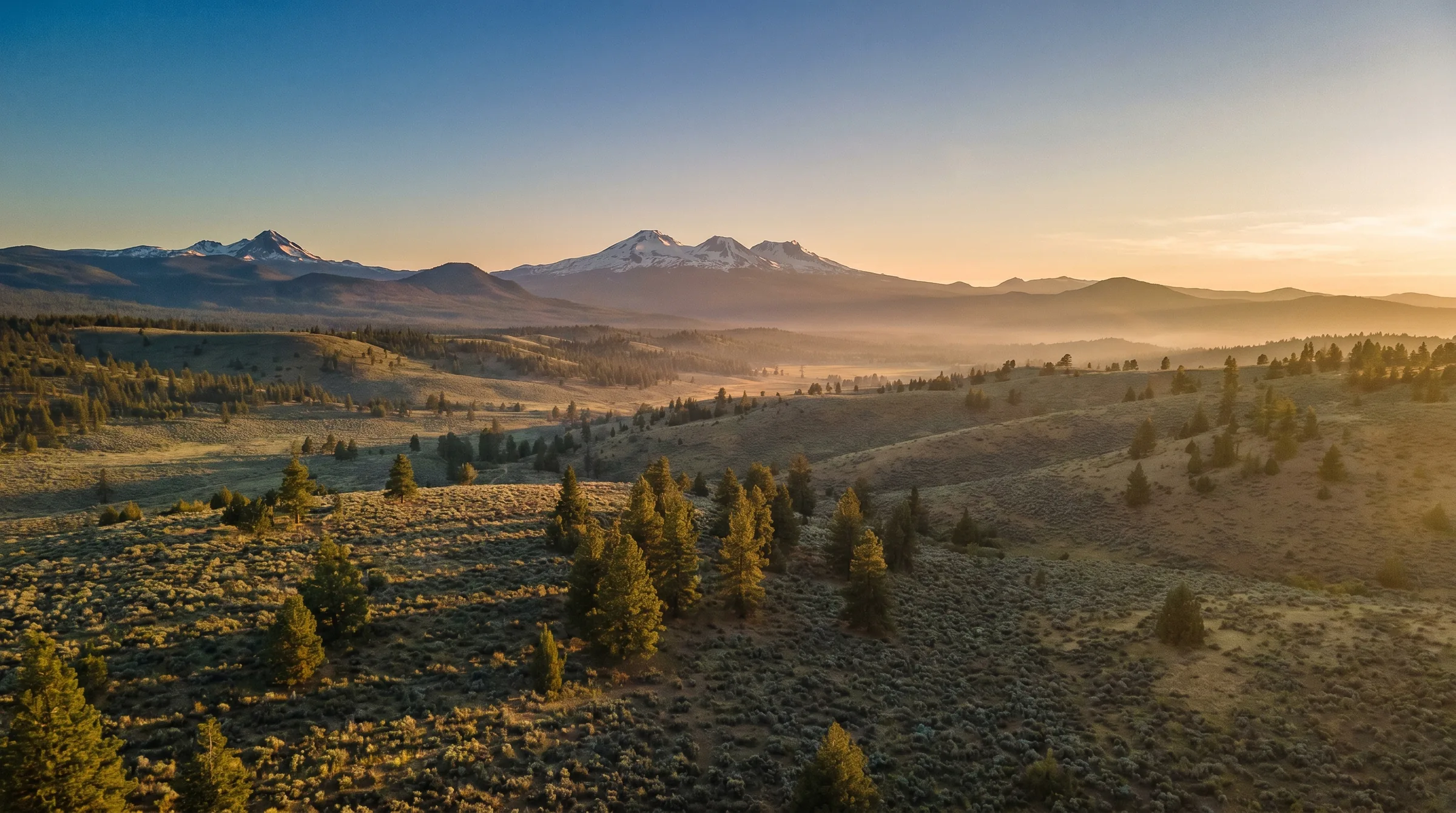 The Three Sisters and Cascade peaks over Central Oregon high desert at golden hour